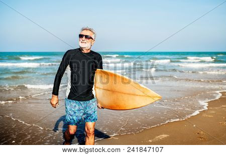 A senior man with a surfboard