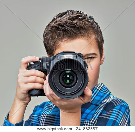 Boy  with dslr camera photographing.  Teen  boy with camera taking pictures.