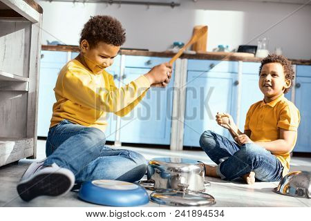 Little Music Lovers. Upbeat Little Boys Playing Music On Saucepans With Wooden Spoons And Having Fun
