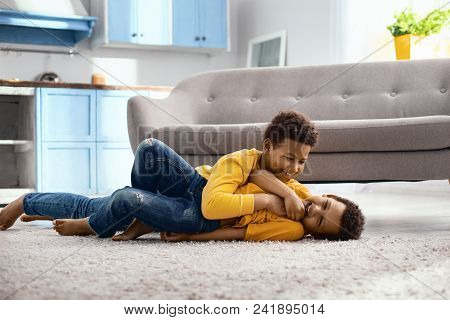 Love You. Cute Little Boy Lying On The Floor And Tickling His Younger Brother While Laughing Loudly 