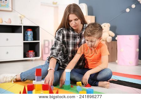Young Woman And Little Boy With Autistic Disorder Playing At Home