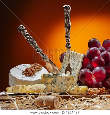 Different Types Of Cheese, Vintage Knife And Fork For Cheese And Grapes. Dark Background. Place For 