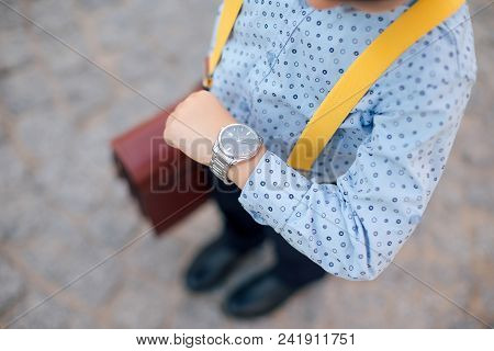 Silver Watch On The Hand Of Future Businessman In Blue Shirt, With Briefcase And Yellow Suspenders. 