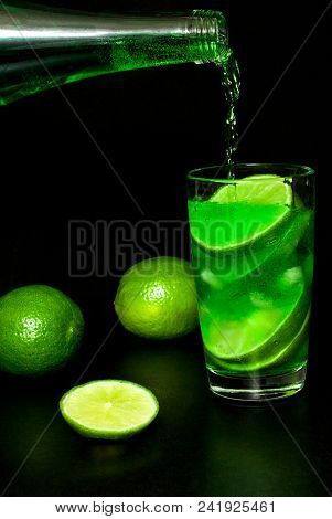 Summer Refreshing And Beverages Concept. Stream Of Cold Lemonade Water From A Bottle Is Poured Into 