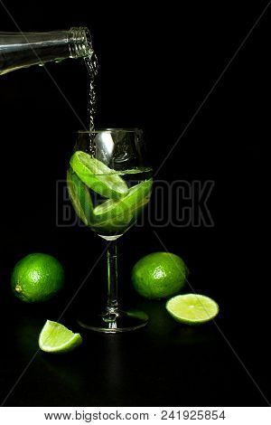 Summer Refreshing And Beverages Concept. Wineglass Of Cold Drink With Ice And Fresh Ripe Slice Green