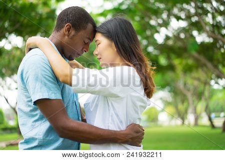 Portrait Of Happy Multiethnic Couple Standing Touching Heads In Park. Asian Woman And African Americ