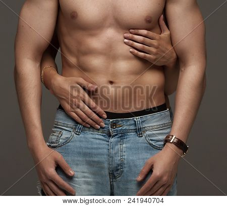 Sexy Muscular Naked Man And Female Hands Unbuckle His Jeans On A Dark Background