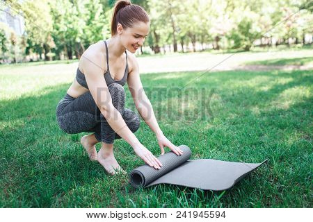 Girl In Grey Sport Costume Is Almost Sitting And Rolling Up The Carimate. She Is Doing That Very Acc
