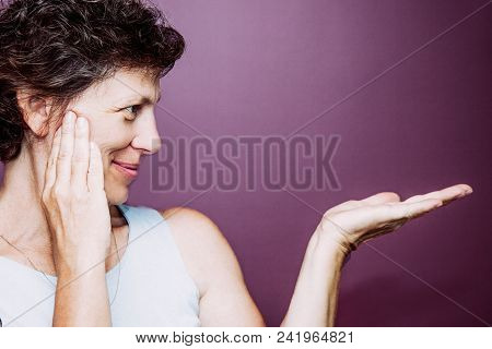 Pretty Senior Woman Pointing Aside. She Admiring Item And Recommending This. Or She Trying To Rememb