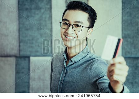 Cheerful Young Asian Businessman Looking At Camera And Showing Credit Card. Successful Man Using Cas