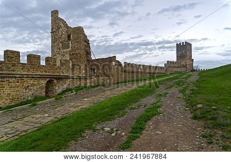 Genoese Fortress In Sudak, Crimea. Towers And Walls Against The Sky. Cloudy Day, Early April.
