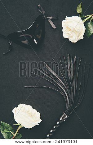 Black Flogging Whip And Mask With White Roses Isolated On Black