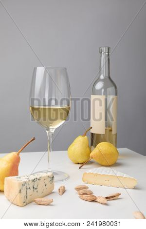 Brie And Dorblu Cheese With Pears, Almond, Wine Glass And Bottle On Gray