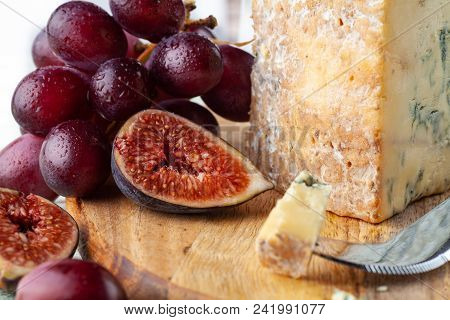 Stilton On A Cheese Board With Red Grapes, Fig And Cheese Knife