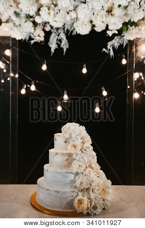 White Wedding Cake With Peonies And Roses Flowers On The Night Ceremony Outdoors. Extra Large Three-