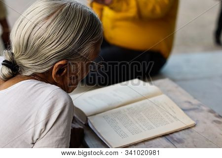 November 30, Maharashtra India, - An Elderly Lady In White Dress Reading Books In The Evening At Gan