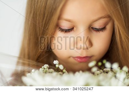 Close Up Beautiful Little Blond Girl With A Bouquet Of Wildflowers With Weathered Lips