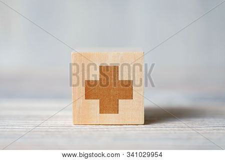 Close Up Of Medical Symbol Of The Cross On Cube On Wooden Background. Concept Of Medical Support, He