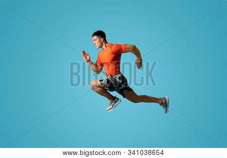 Athletic Young Man Running On Light Blue Background, Side View