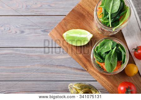 Flat Lay Composition With Jars Of Healthy Food On Light Grey Wooden Background, Space For Text