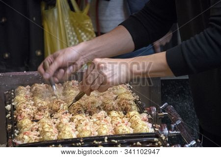 Vendor Making Takoyaki On A Takoyaki Pan In Osaka, Japan. Takoyaki Is Famous Street Food In Osaka.