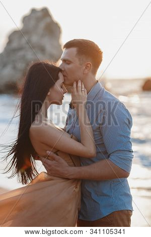 Couple In Love At Dawn By The Sea. Honeymoon Trip. Man And Woman Traveling. Happy Couple By The Sea 