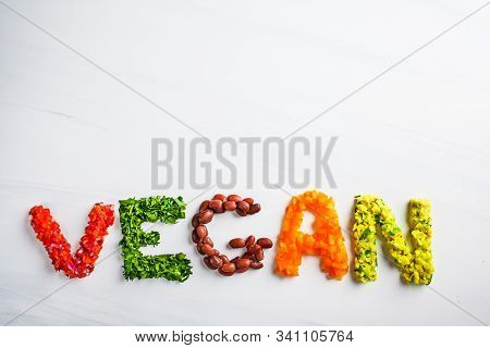 The Word Vegan On A White Background, Top View. Vegan Food Concept. Vegan Composed Of Beans, Guacamo