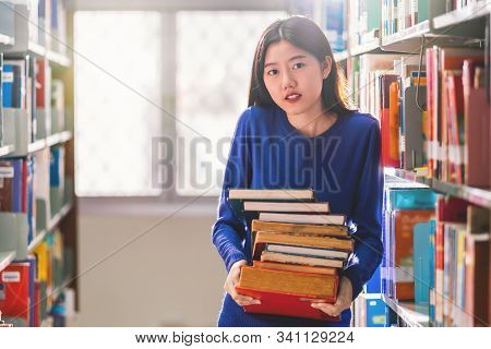 Asian Young Student In Casual Suit Holding After Searching The Book From Book Shelf In Library Of Un