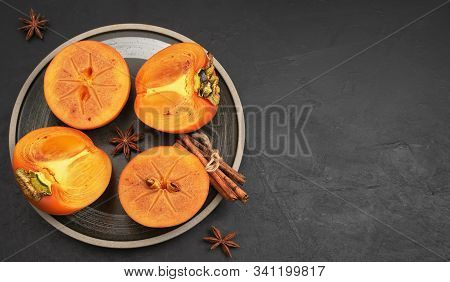 Delicious Fresh Persimmon Fruit On A Black Background. Persimmon Slices On A Black Plate. Copy Space