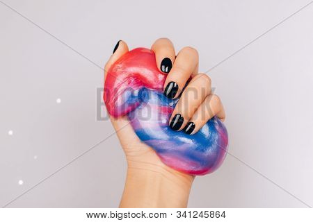 Hands With Black Manicure Holding Slime In Blue And Pink Vibrant Colors