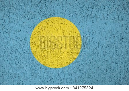 Palau Flag Depicted In Bright Paint Colors On Old Relief Plastering Wall. Textured Banner On Rough B
