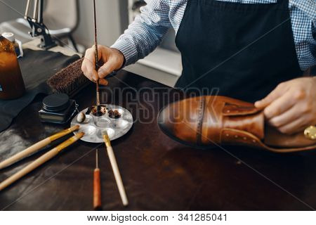 Bootmaker with brush tints shoes, footwear repair