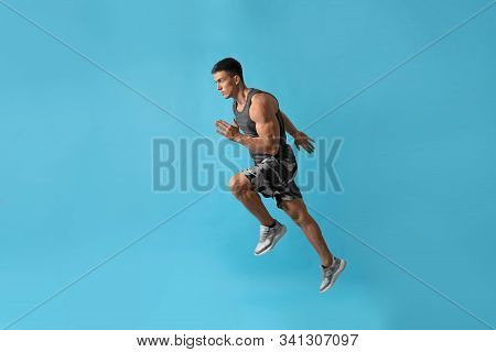 Athletic Young Man Running On Light Blue Background, Side View