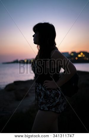 Sideways Potrait Black Silhouette Of A Young Woman In A Port Seashore With A Beautiful Urban Bokeh. 