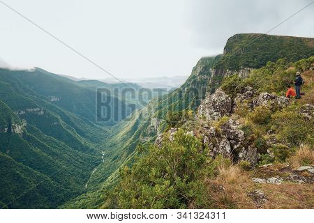 Cambara Do Sul, Brazil, July 17, 2019. People On Steep Rocky Cliffs In Fortaleza Canyon With Fog Com