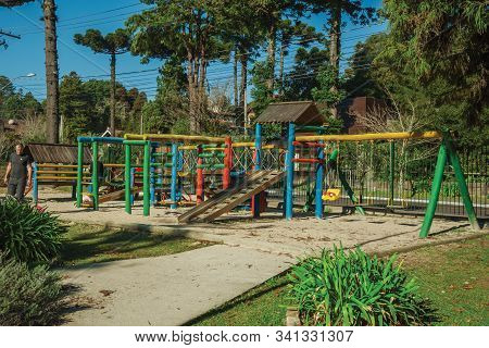 Gramado, Brazil - July 21, 2019. Colorful Playground Equipment Among Trees With Children And Adults 