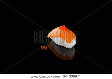 Sushi Nigiri With Salmon - Syake With Red Caviar On A Black Background With Reflection. A Dish Of Ri