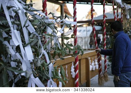 Details In A Japanese Shinto Shrine With A Maan Praying Blurred In The Background