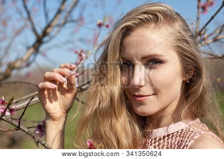 Beautiful Blonde Woman In Pink Dress Walks Through The Flowering Garden Spring