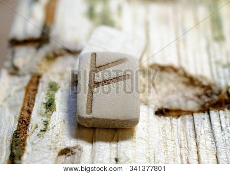 Wooden Rune Fehu Close-up On A Wooden Background. Soft Focus