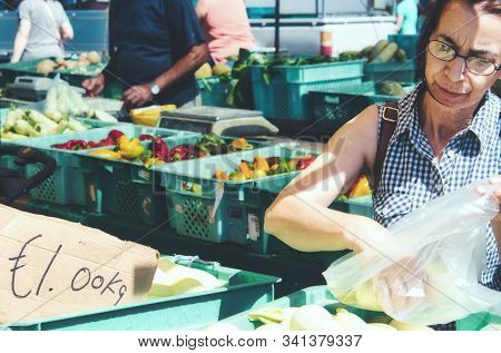 Attard / Malta - September 7 2019: Middle-aged Woman Buying Fresh Vegetables At An Open-air Market S