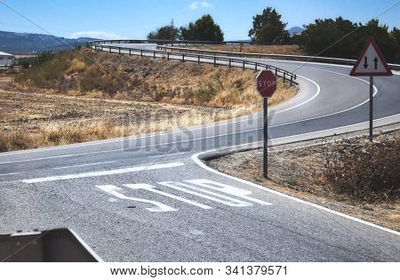 Stop Sign And Markings On The Road At A Two-way Crossroad In A Rural Countryside Scene