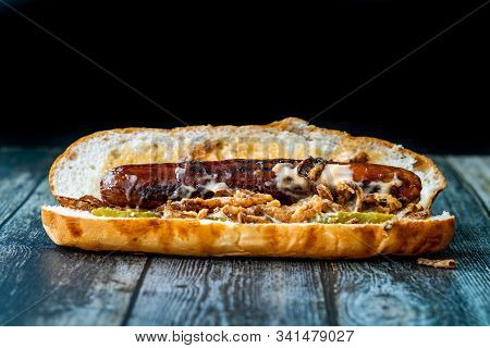 Hot Dog With Caramelized Onion, Cheddar And Gruyere Cheese Sauce On Wooden Surface With Potatoes.