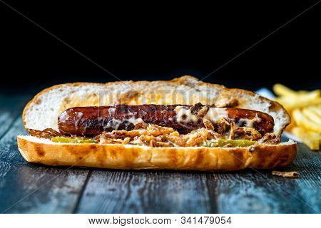 Hot Dog With Caramelized Onion, Cheddar And Gruyere Cheese Sauce On Wooden Surface With Potatoes.