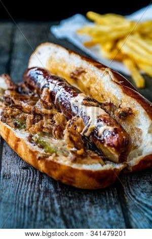 Hot Dog With Caramelized Onion, Cheddar And Gruyere Cheese Sauce On Wooden Surface With Potatoes.