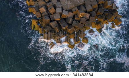 Aerial View Of A Person Sitting On The Gold Coast Spit Breakwall, With The Ocean Washing Over The Ro