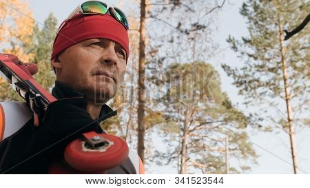 Training An Athlete On The Roller Skaters. Biathlon Ride On The Roller Skis With Ski Poles, In The H