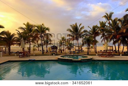 Pool And Sea. Palm Trees. Colored Sky. Sunset. Nice View Of The Beach.