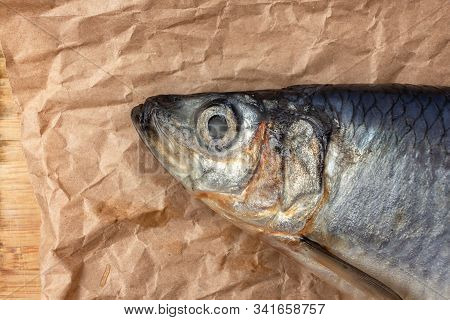 Delicious Salted Herring On Parchment Paper, Fish Head Close-up. The Counter Of The Fish Shop