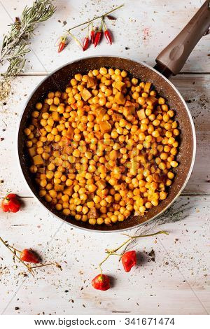 high angle view of a frypan with a vegetarian chickpea stew with seitan, on a rustic wooden table